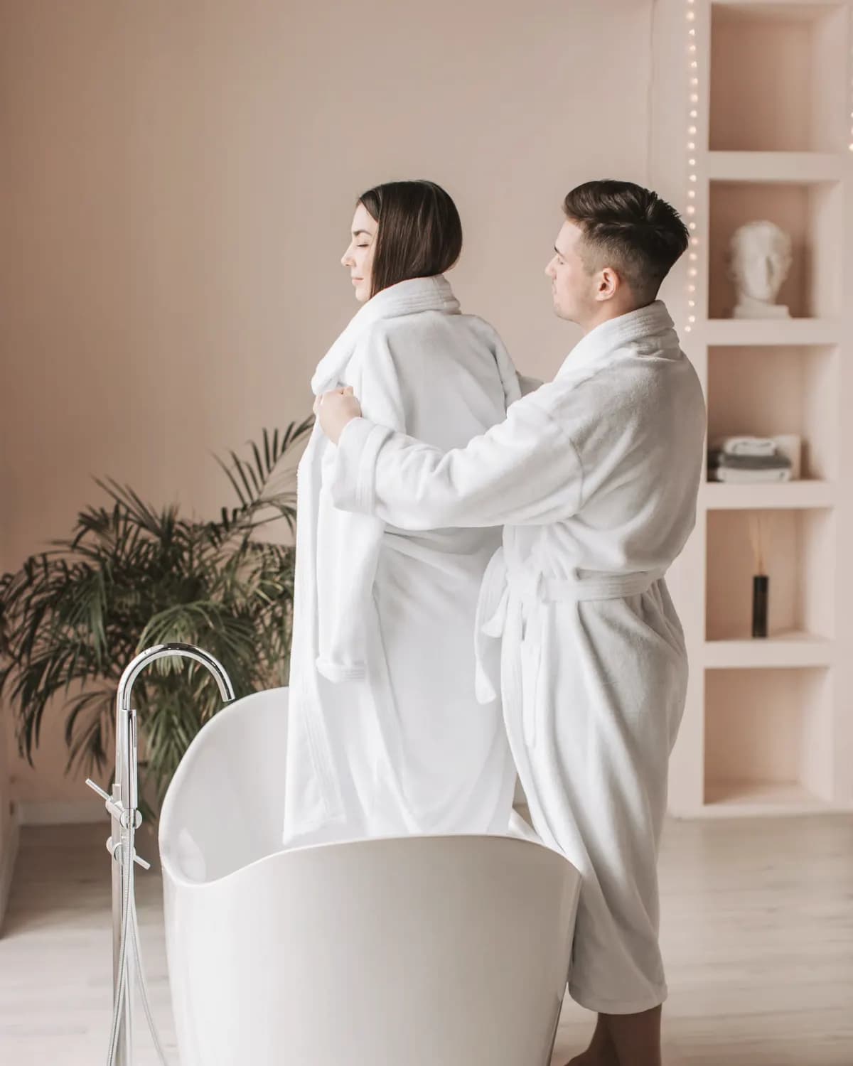 Couple in white bathrobes in a bright spa bathroom